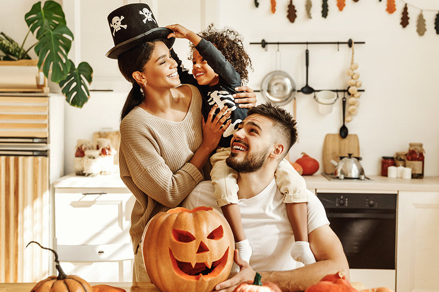 Family Carving Pumpkins and Trying on Halloween Costumes in the Kitchen