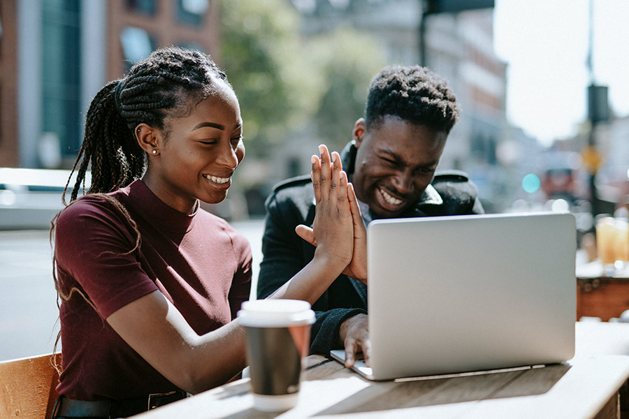 Happy Couple High Fiving While Looking at Laptop