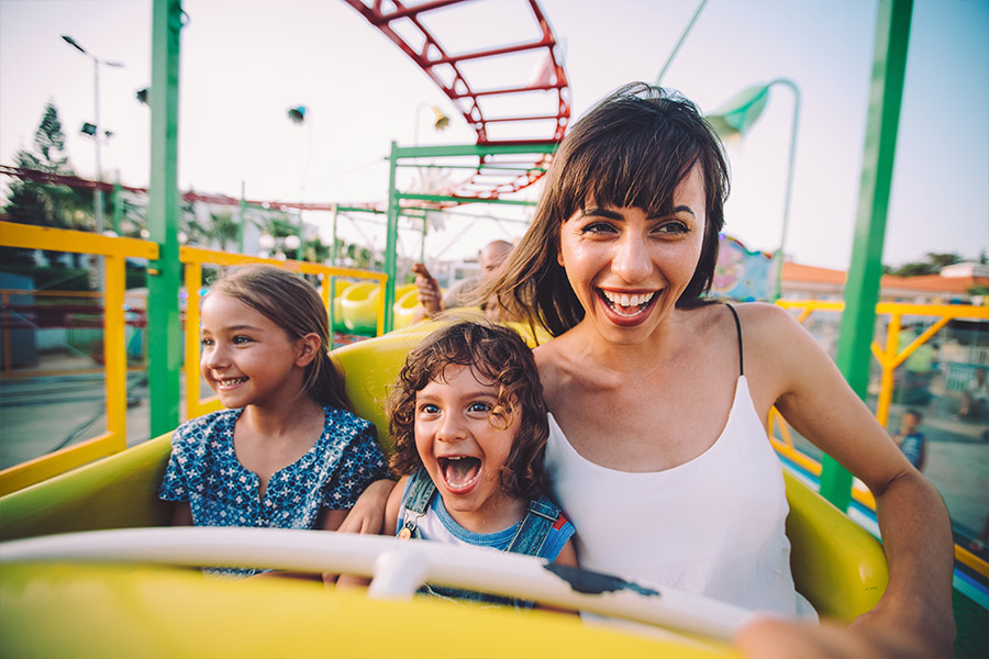 Happy Mother and Children on Roller Coaster During Spring Break