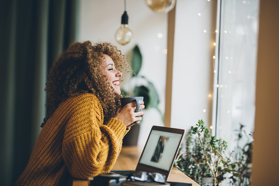 Woman wearing a sweater and drinking a warm beverage.