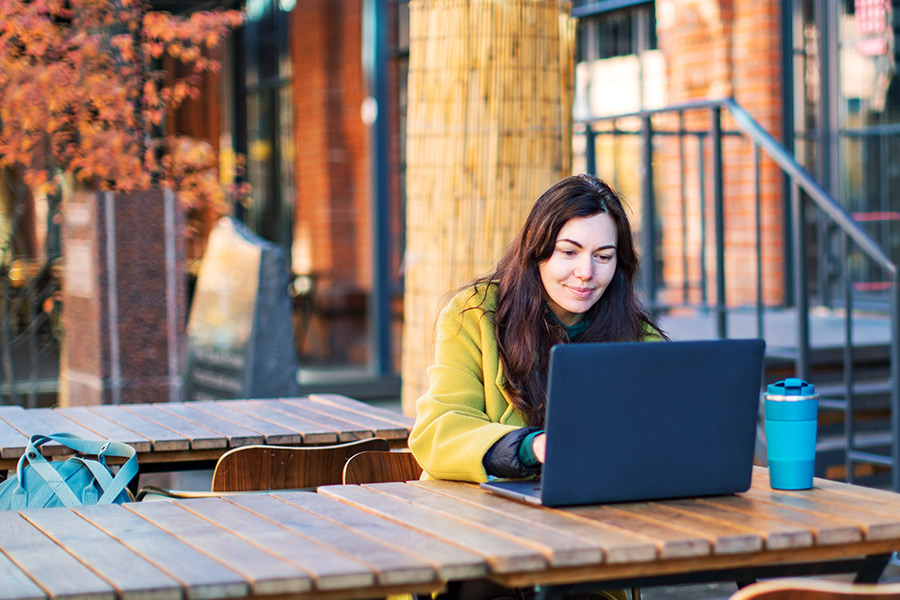 Woman on Laptop at Outdoor Cafe in the Fall - Check `n Go