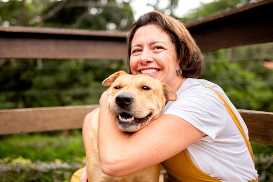 Smiling Woman in White T-Shirt Hugging Her Dog Outside