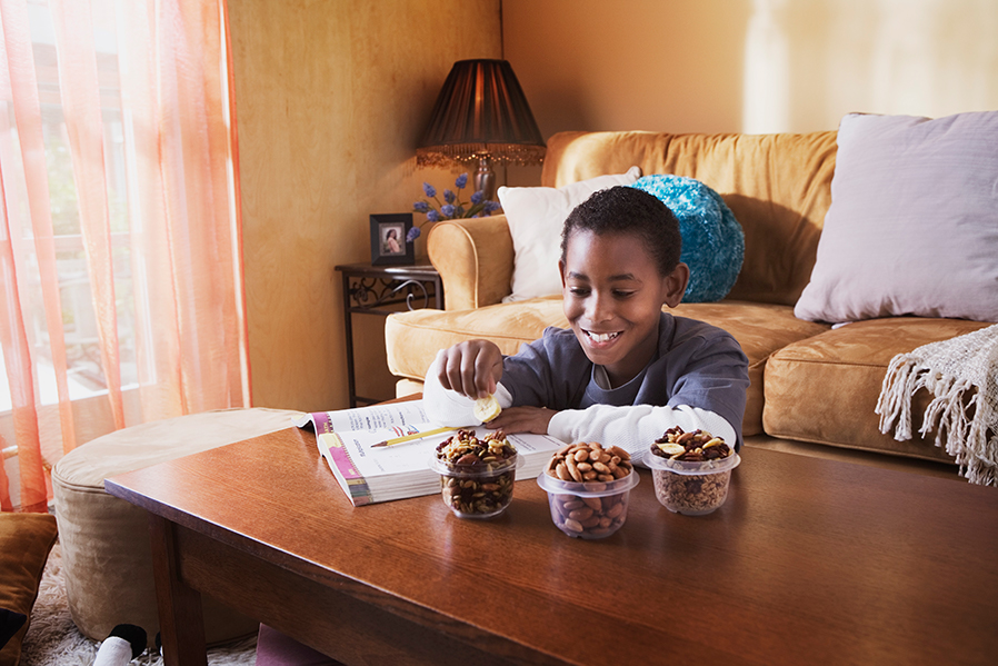 Young boy eating a snack and doing his homework.