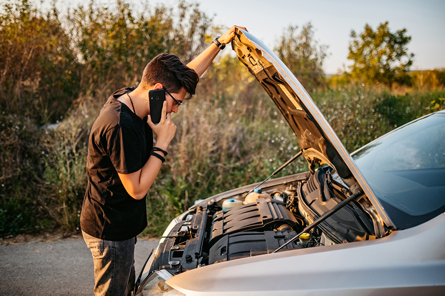 Man with a broken down car trying to fix it.