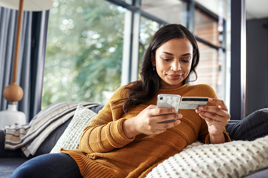 Woman Reviewing Credit Card with Phone in Hand