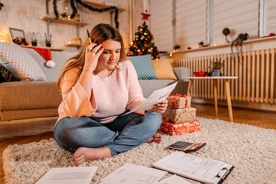 Woman Reviewing Finances with Christmas Gifts Nearby