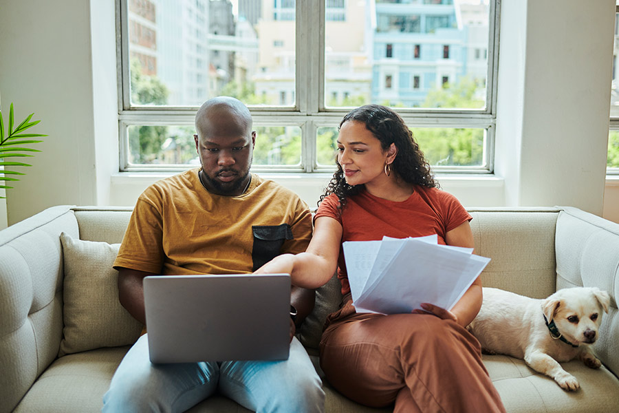 Young Couple Reviewing Credit Score Documents and Laptop Screen