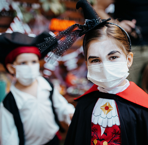 Girl dressed as a vampire wearing a protective face mask on Halloween.