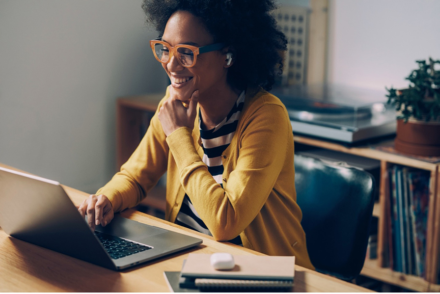 A woman smiles while looking at her laptop