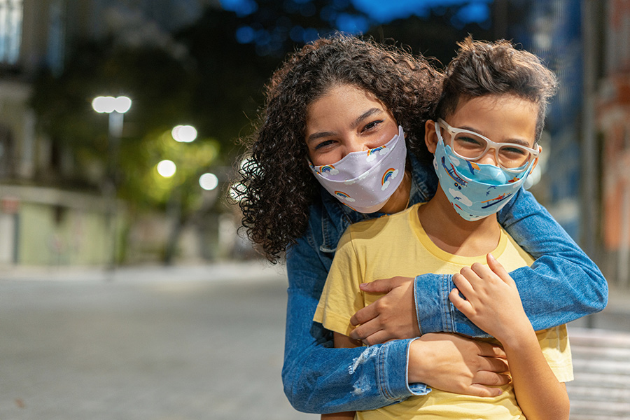 Siblings with N95 respiratory mask outdoors at night